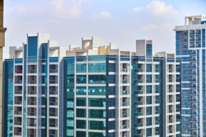A cityscape view of modern high-rise buildings with reflective glass facades under a blue sky.
